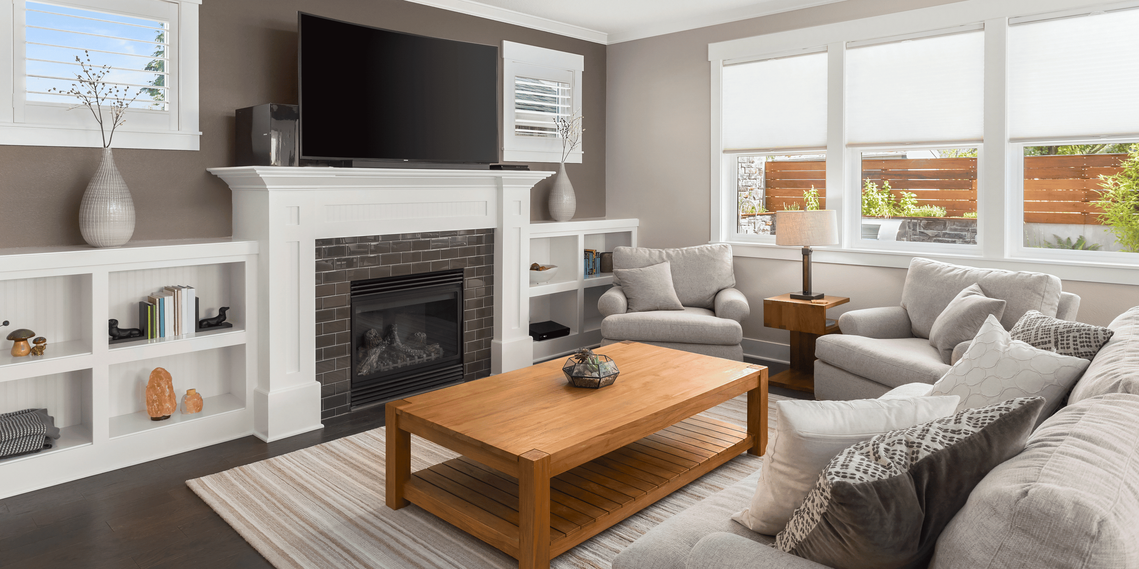 Cozy modern living room with gray sofas, wooden coffee table, and white fireplace