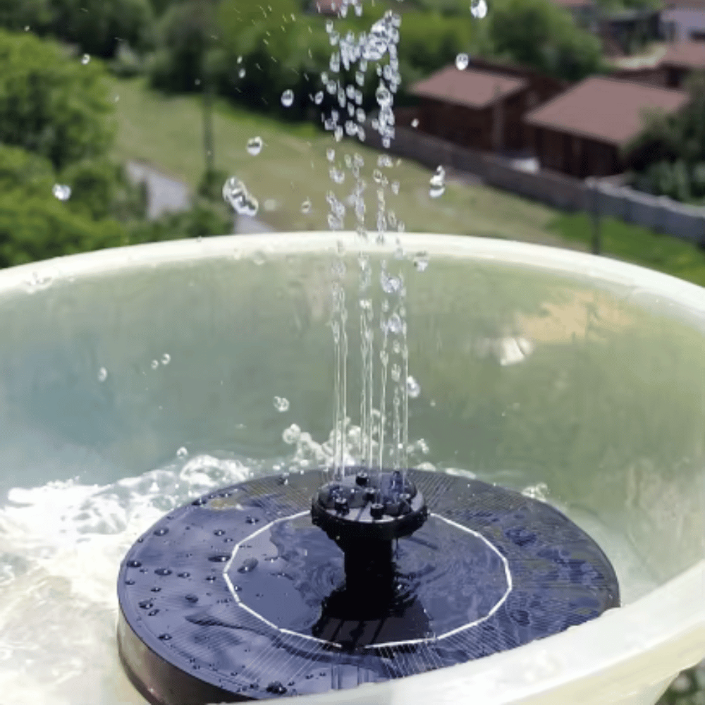 Solar fountain pump spraying water inside a birdbath with a garden background