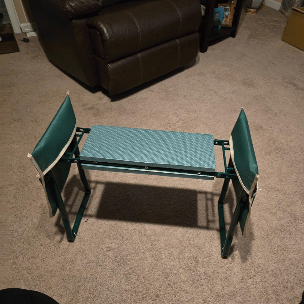 Green folding garden kneeler with side handles placed on beige carpet in a living room