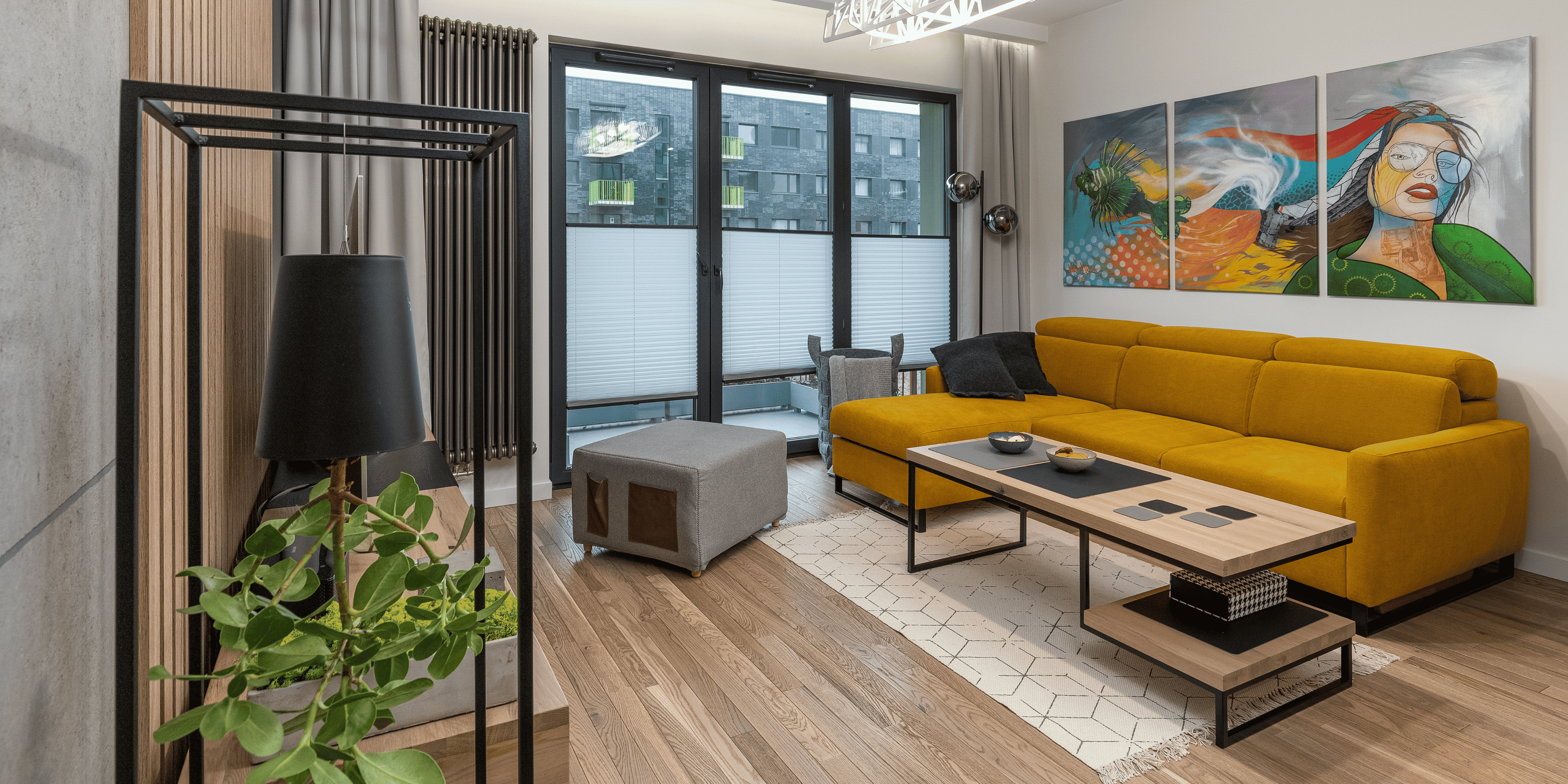 Modern living room with yellow sofa, urban view through large windows, and colorful abstract artwork on the wall